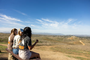 Sasquatch Outdoor Horizon and Silhouette Shirt Onsite Lifestyle Trio Sitting on a Bench