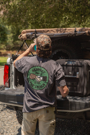 Sasquatch Outdoor Respect The Locals Shirt Onsite Photo with man facing away from camera drinking sports drink near truck